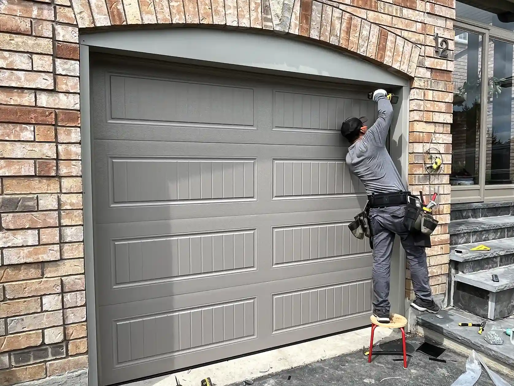 Technician installing a garage door on a brick home in Toronto